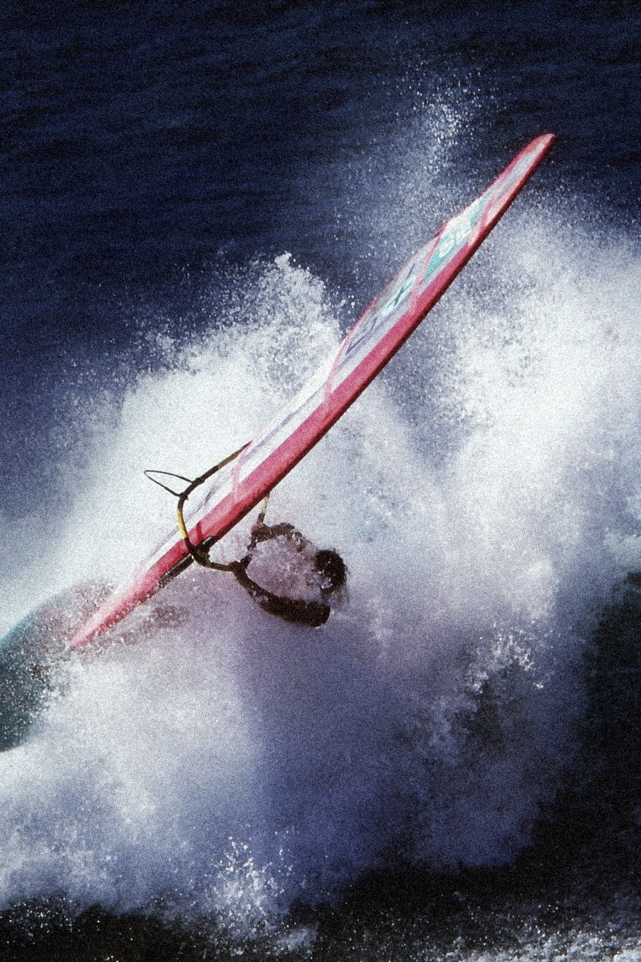 1990s windsurfer carving through a breaking wave on a pink board